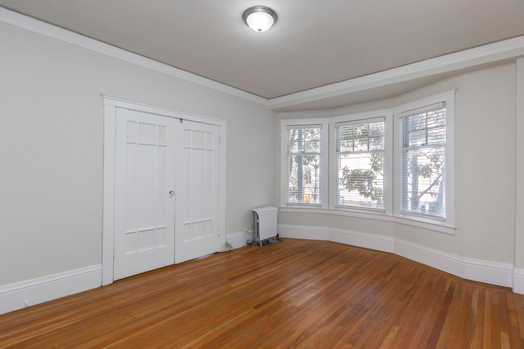 a living room with wood floors and white walls and a white door