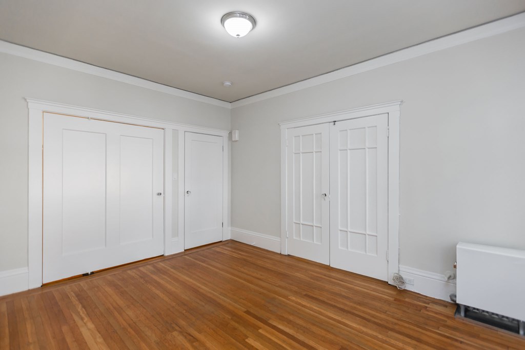 a bedroom with white walls and wood floors and white doors