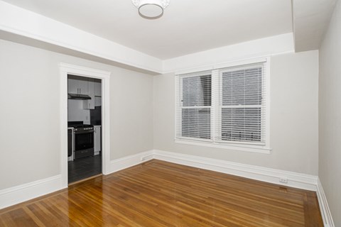A room with a wooden floor and a window with blinds.