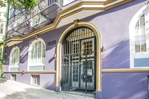 A purple building with a black gate and windows.