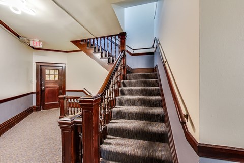 A staircase with a carpeted floor and wooden banister.