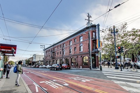 A street scene with a red brick building and a tram line running down the middle of the road.