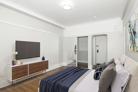 A bedroom with a bed, a television, and a painting on the wall.