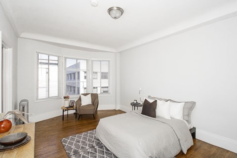 A bedroom with a large bed and a chair.