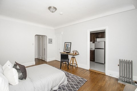 A white bedroom with a bed, desk, and chair.