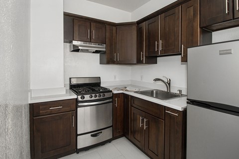 A kitchen with a stove, sink, and refrigerator.