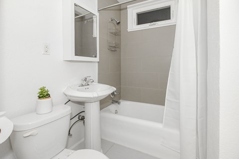 A white bathroom with a toilet, sink, and bathtub.