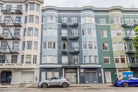 A row of multi-story buildings with balconies and fire escapes.