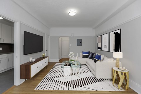 A modern living room with a white sofa, a coffee table, and a TV.