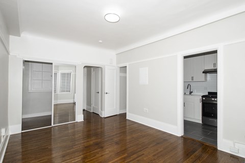 A spacious, empty room with wooden floors and white walls.