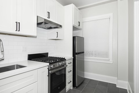 A kitchen with white cabinets and a black stove top oven.