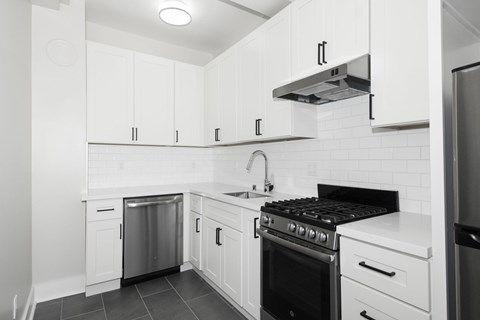 A modern kitchen with white cabinets and a black stove top.