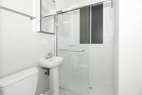 A white bathroom with a sink, toilet and shower.
