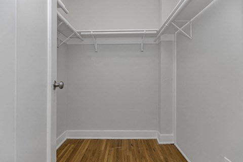 A white closet with a door and a wooden floor.
