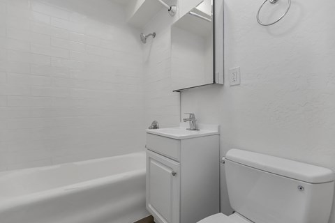A white bathroom with a tub, toilet, and sink.
