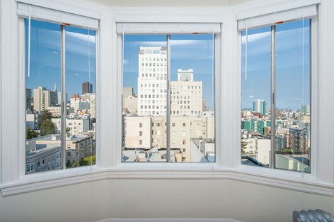 A white chair is in front of a window with a view of a city.