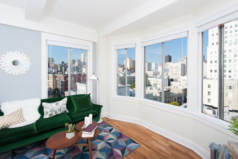 A living room with a green couch and a view of the city.
