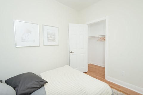 A bedroom with a bed, two pillows, and two pictures on the wall.