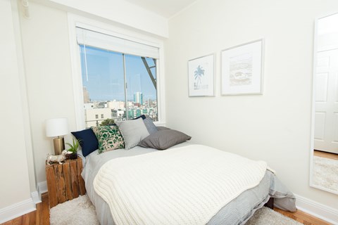 A bedroom with a large bed and a window overlooking the city.