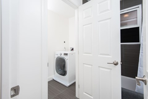 A white door is open to a laundry room with a washing machine.