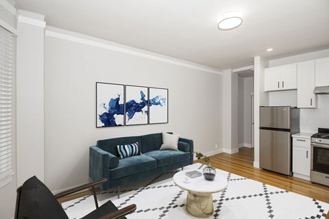 A living room with a blue couch and a painting on the wall.