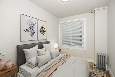 A bedroom with a bed, a nightstand with a lamp, and a framed picture of a deer head on the wall.