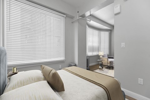 A bedroom with a large bed and a window with blinds.