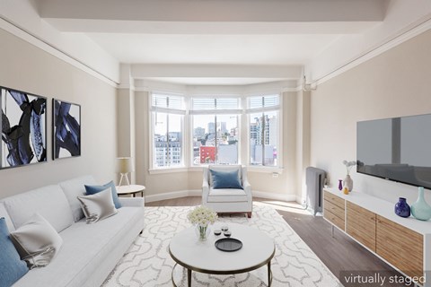 A living room with a white couch, a coffee table, and a large window.