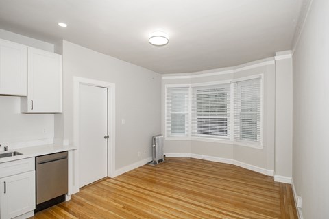 A kitchen with white cabinets and a wooden floor.