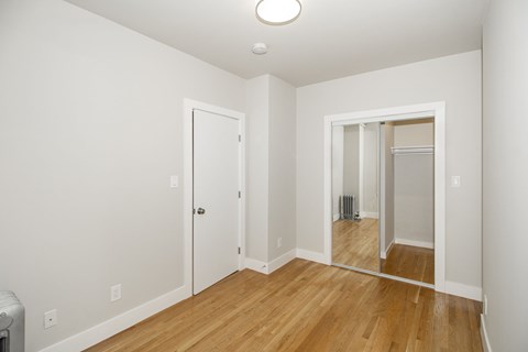 A room with a white door and a mirror on the wall.