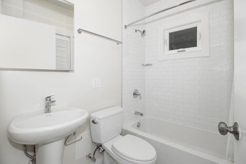 A white bathroom with a toilet, sink, and bathtub.