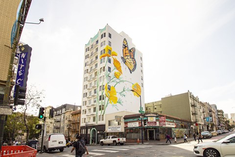 A street scene with a large building with a mural of a butterfly on it.