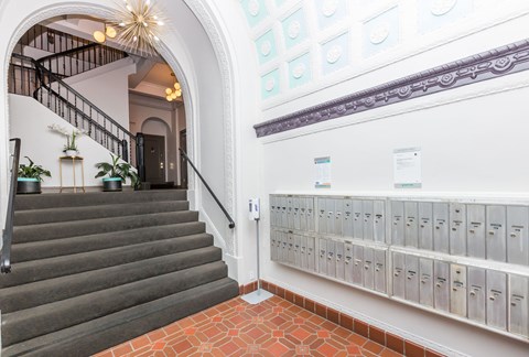 A staircase with a chandelier and a wall of mailboxes.