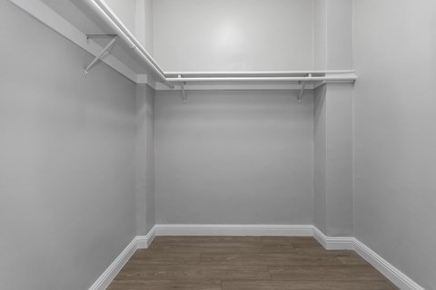A white wall with a wooden floor and a white shelf.