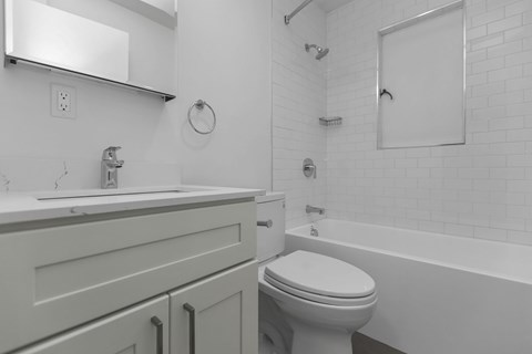 A white bathroom with a toilet, sink, and bathtub.