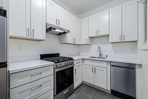 A kitchen with white cabinets and a black stove top.