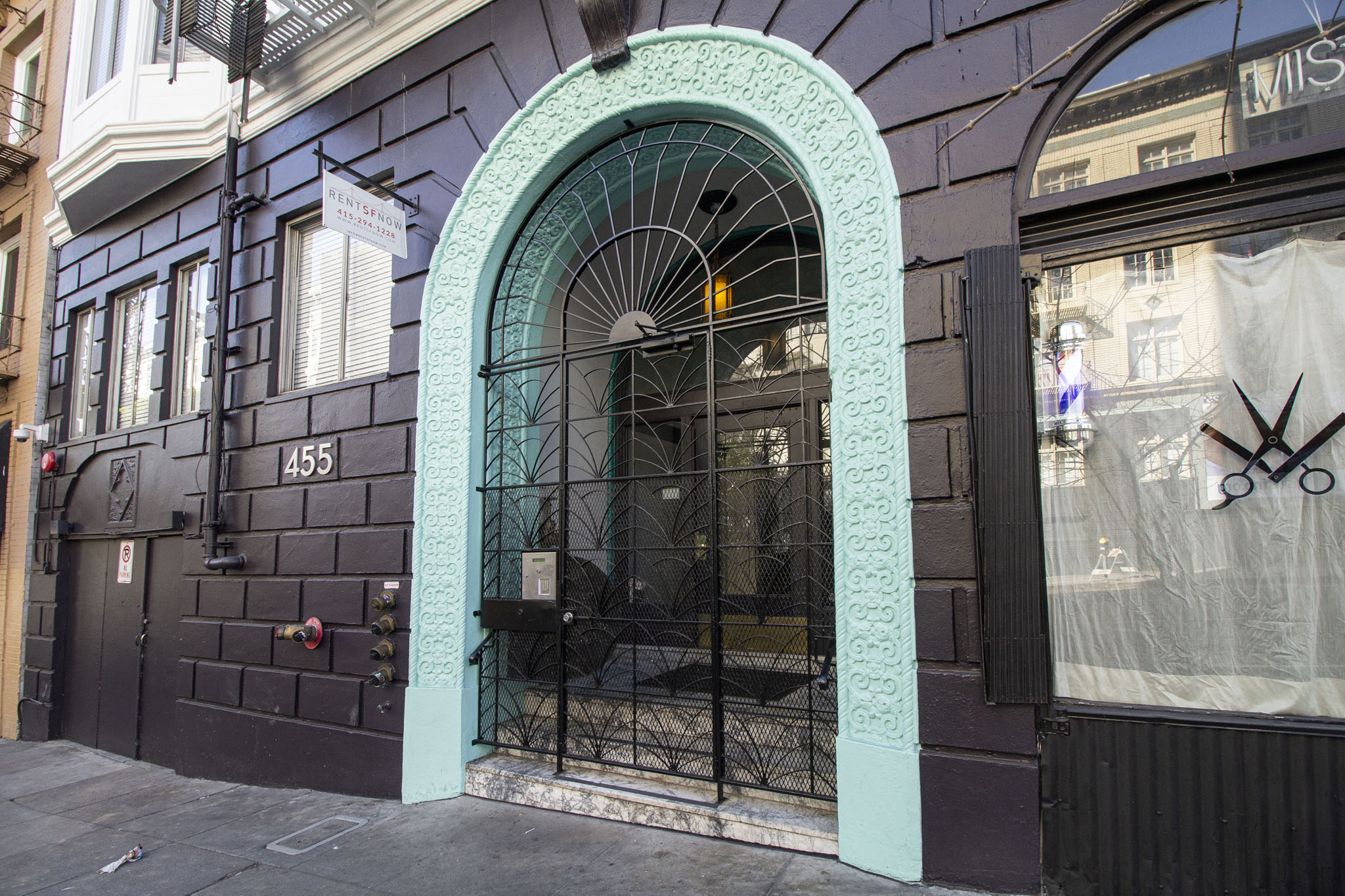 A black building with a turquoise arched doorway.