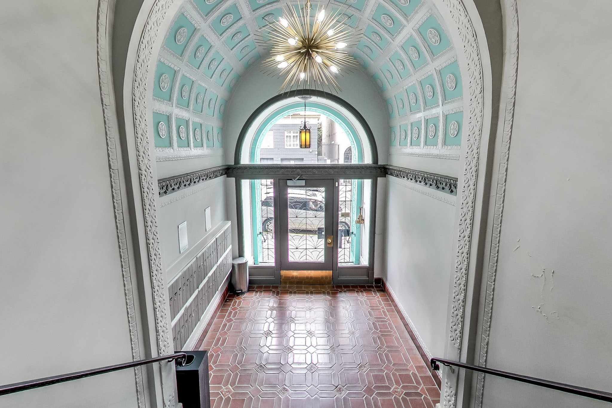 A hallway with a red tiled floor and white walls.
