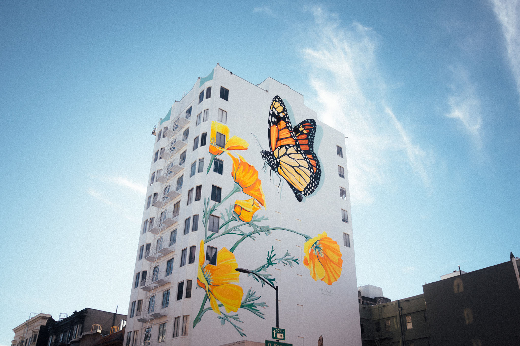 A large mural of a butterfly and flowers is painted on the side of a white building.