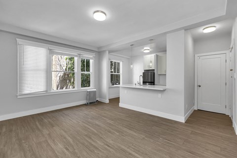A spacious room with wooden flooring and white walls.