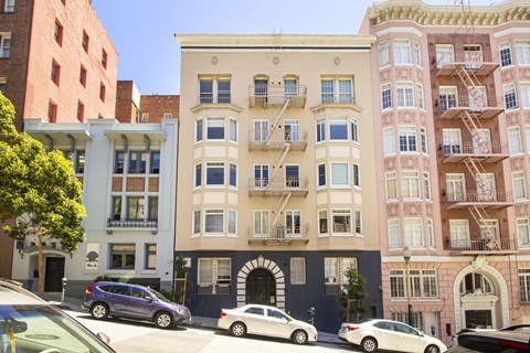 A row of buildings with cars parked in front.