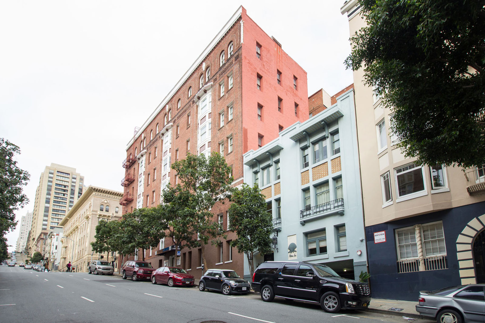 Cars parked on the side of a street in front of a red building.