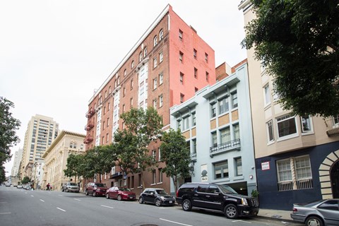 Cars parked on the side of a street in front of a red building.