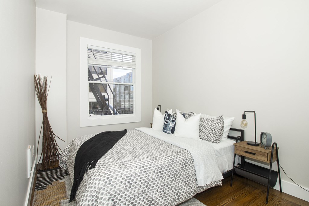 A bedroom with a bed, nightstand, and a picture on the wall.