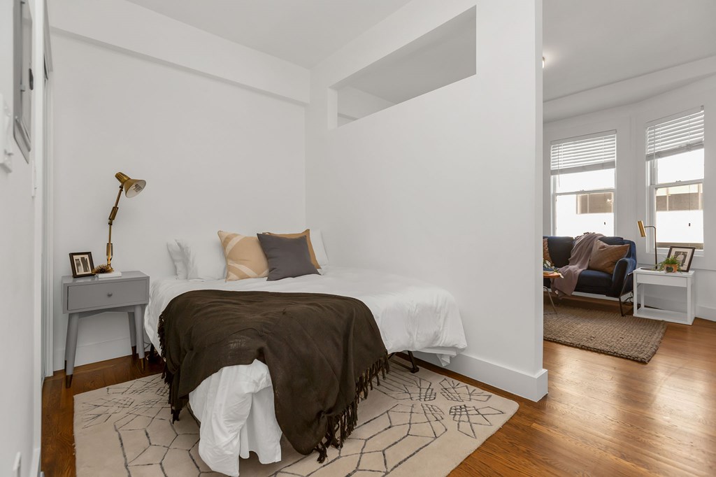 A bedroom with a bed, a chair, and a table.