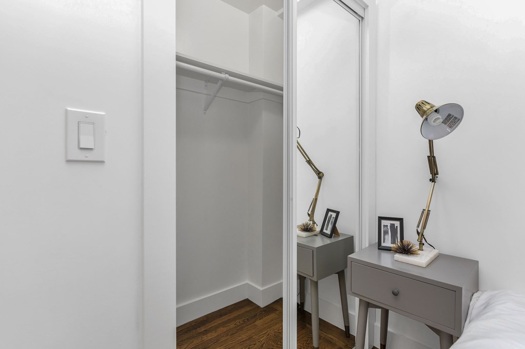 A white bedroom with a grey desk and a mirror.