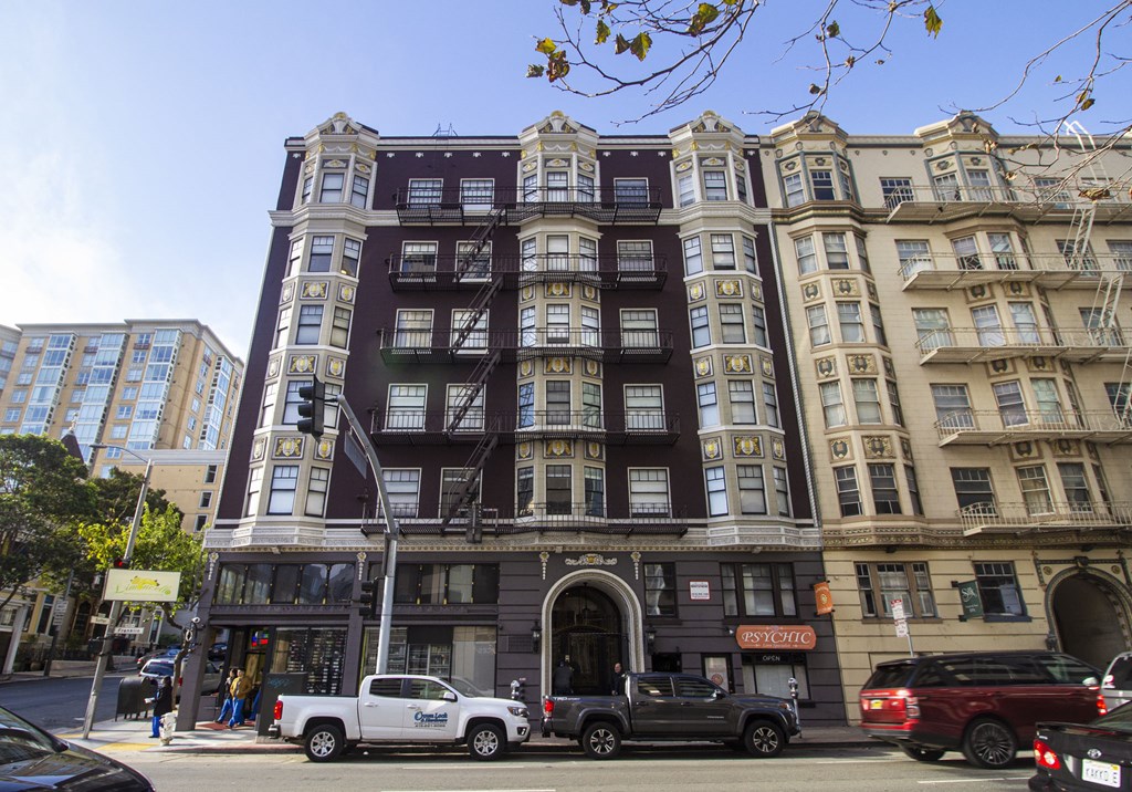A tall building with a dark brown facade stands between two other buildings.