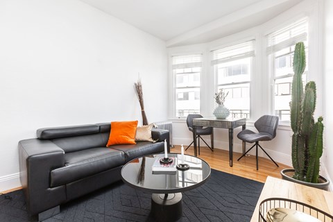 a living room with a black leather couch and a table with two chairs