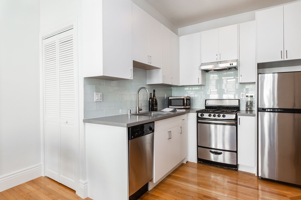 a kitchen with white cabinets and stainless steel appliances