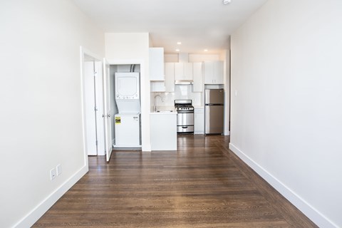 A kitchen with white appliances and wooden floors.